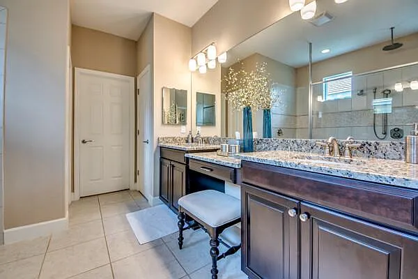 Master bathroom with double vanity, granite countertops, makeup stool, and walk-in shower
