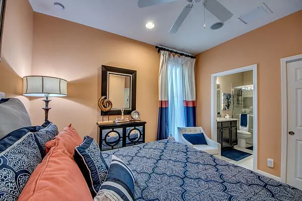 Guest bedroom with queen bed, coral/blue bedding, and en-suite bathroom door