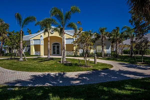 Sandoval clubhouse exterior — yellow building with palms and paver drive