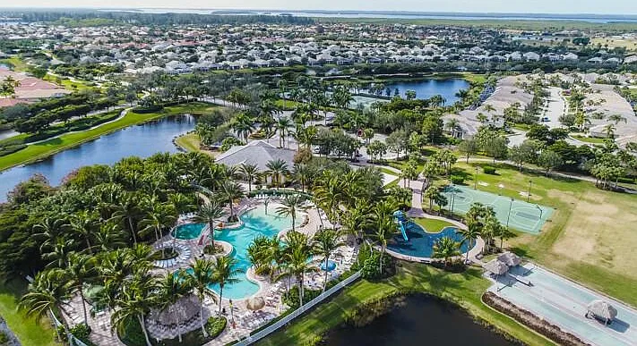 Aerial view of Sandoval resort pool complex with water slide, tiki huts, and palms