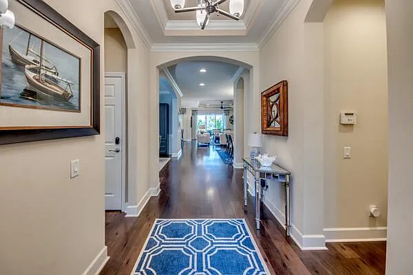 Entry foyer with arched doorways, hardwood floors, and blue geometric rug