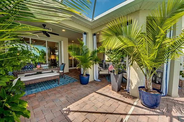 Outdoor chaise lounge on brick pavers with tropical potted palms