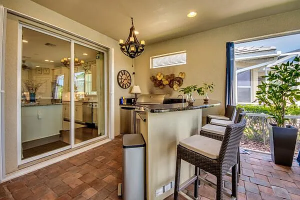 Outdoor kitchen with grill, granite bar top, bar stools, and sliding glass door