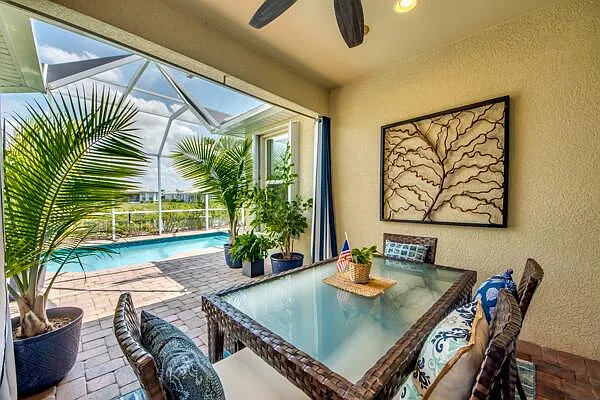 Covered lanai outdoor dining with pool view through the screen enclosure