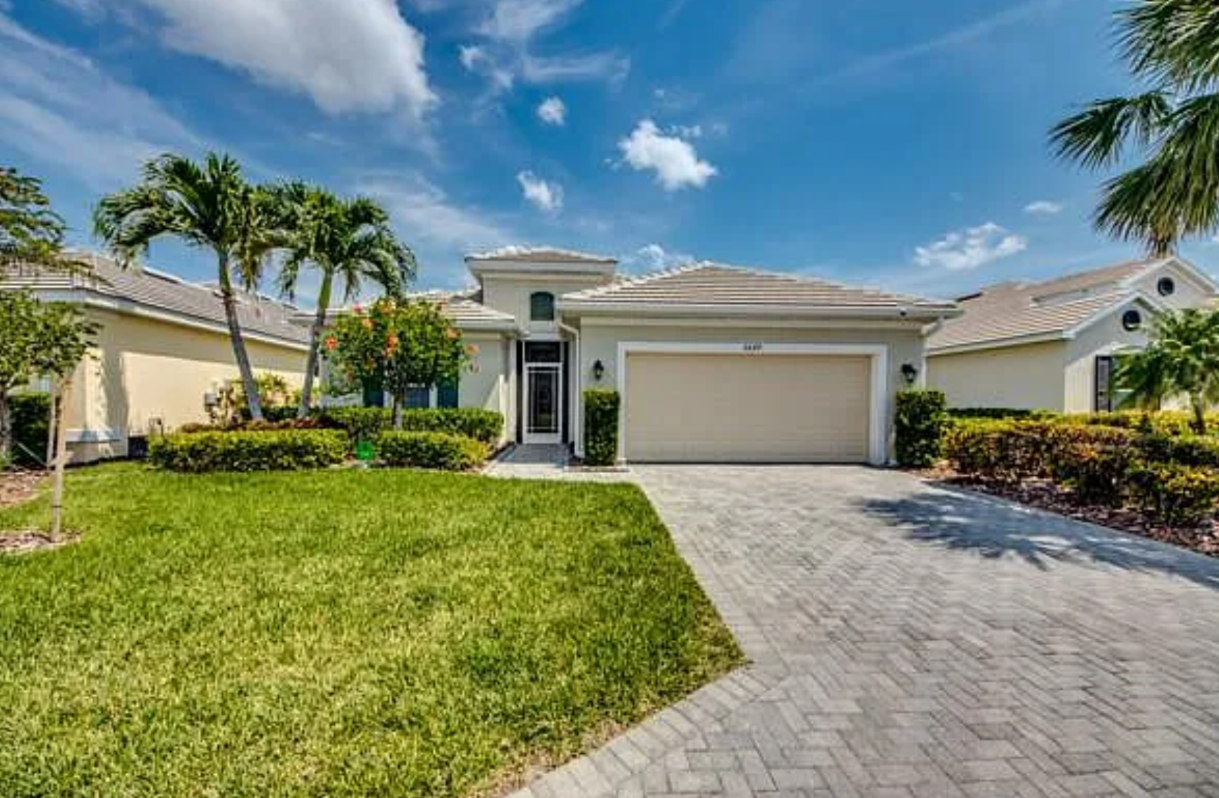Front exterior of the tile-roof home with paver driveway and manicured lawn