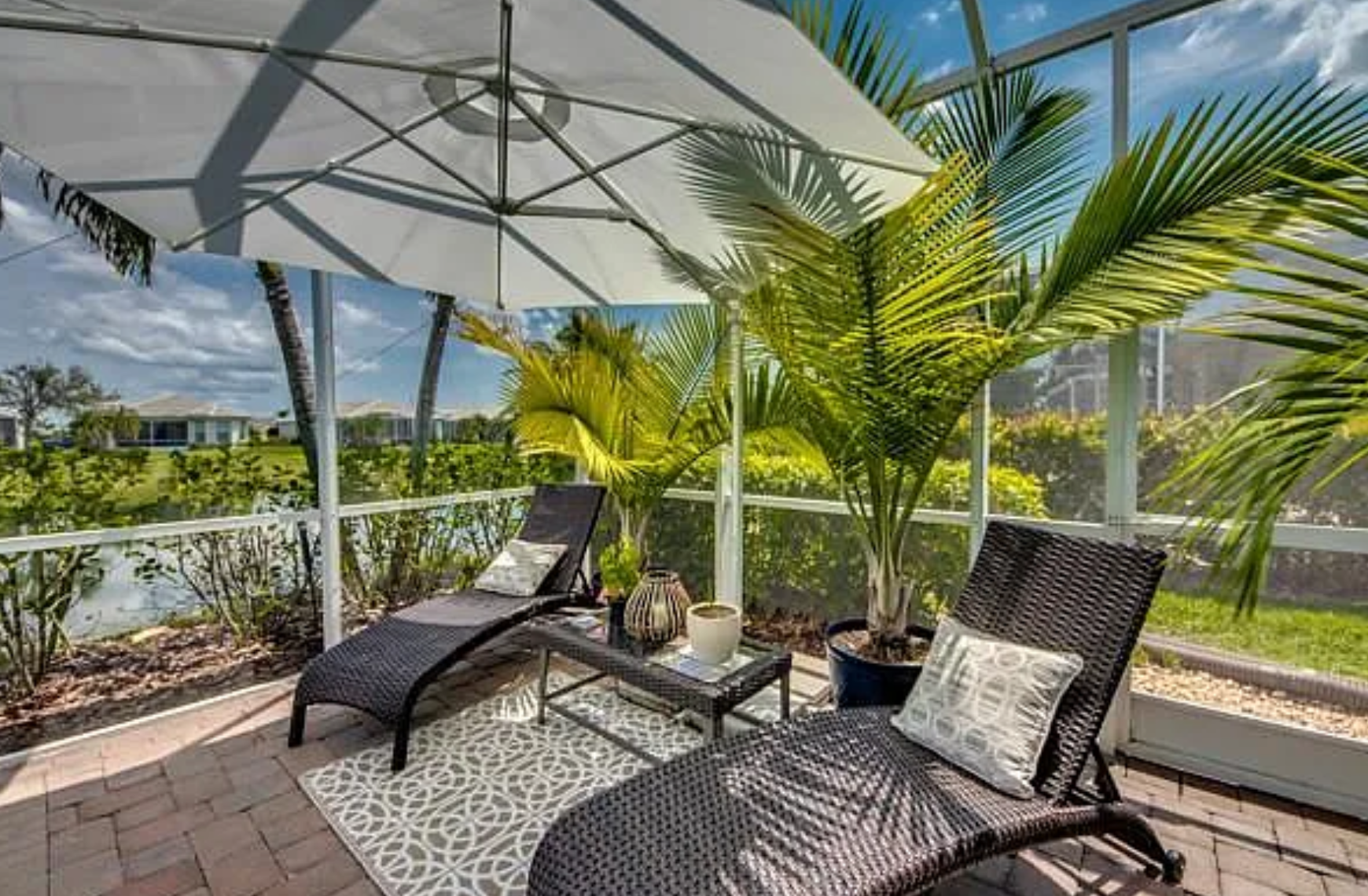 Shaded lanai lounge area with wicker chairs and palm view